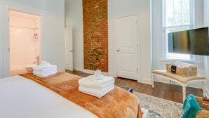 Una habitación de hotel con una cama grande, una pared de ladrillo, un televisor y una ventana con persianas.