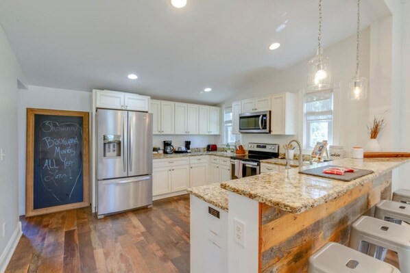 A modern kitchen with white cabinets, stainless steel appliances, and a granite countertop.