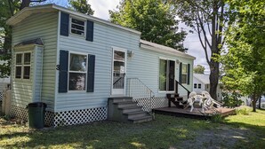 A single-story house with a front porch, a small set of stairs, and a fenced yard. - Park unit #3 for rent by Silver Lake NY  (Perry)