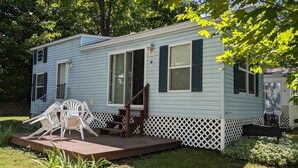A mobile home with a porch, a set of stairs, and a white chair. - Park unit #3 for rent by Silver Lake NY  (Perry)