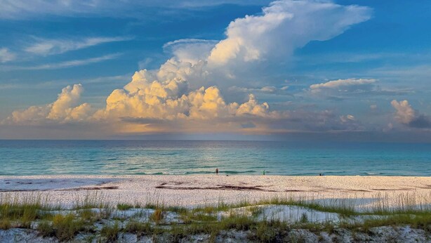 A beach with a clear sky and large clouds.