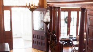 A statue with a torch, a chandelier, and a wooden door with a grid pattern.