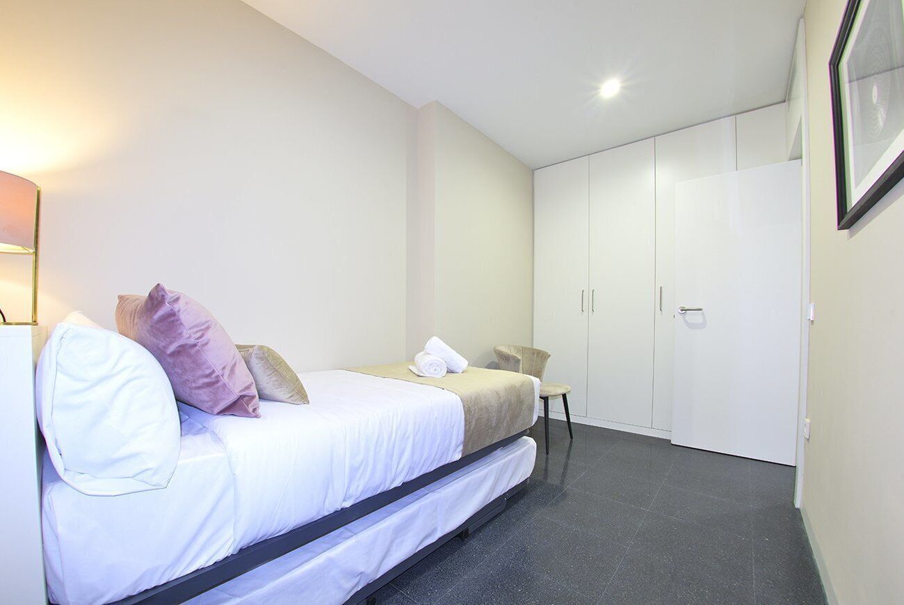 A bedroom with a bed, a chair, and a wardrobe.
