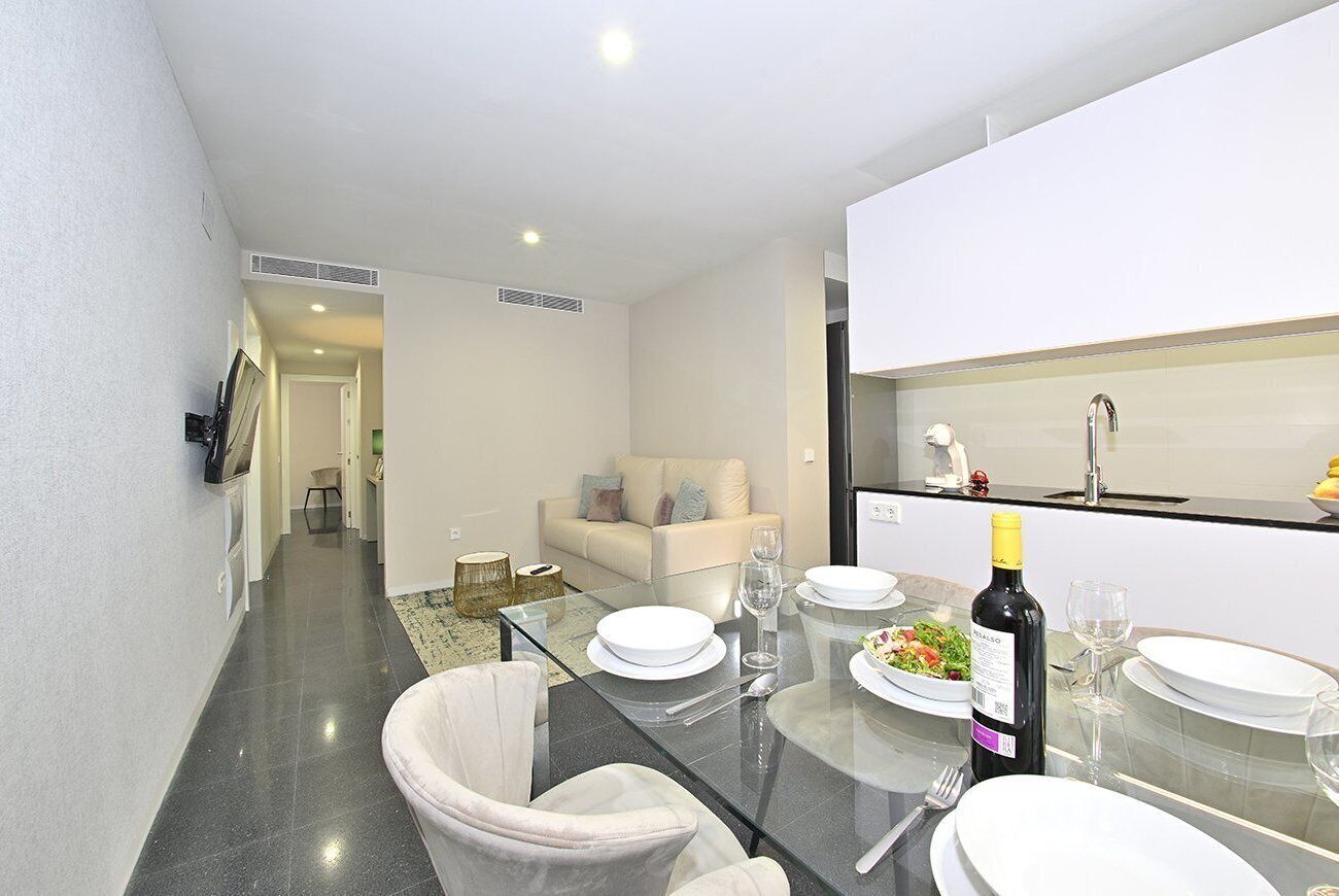 A modern kitchen with a dining table set for four, a refrigerator, and a microwave.