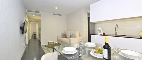 A modern kitchen with a dining table set for four, a refrigerator, and a microwave.