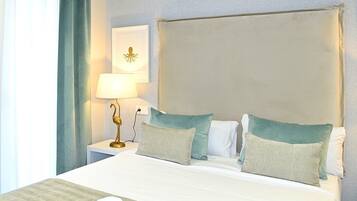 A hotel room with a large bed, two pillows, a nightstand with a lamp, and a wall-mounted picture.