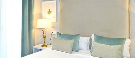 A hotel room with a large bed, two pillows, a nightstand with a lamp, and a wall-mounted picture.