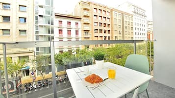 A balcony with a table set for breakfast, including croissant, juice, and coffee.