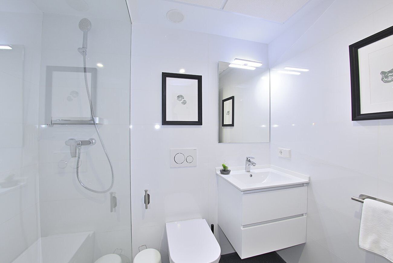 Une salle de bain moderne avec une douche à parois de verre, un lavabo blanc et des toilettes.