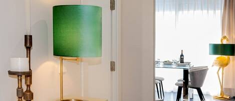 A modern hotel room with a dining area visible through an open door.