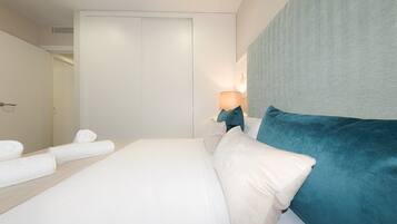 Un dormitorio con cama, mesita de noche, lámpara y puerta.