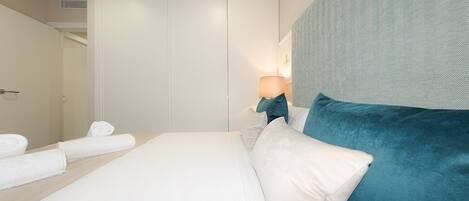 Un dormitorio con cama, mesita de noche, lámpara y puerta.