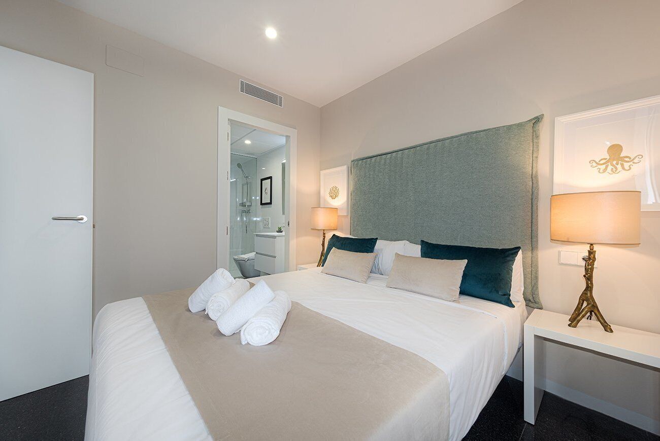 A hotel room with a large bed, a bedside table with a lamp, and a bathroom visible through an open door.