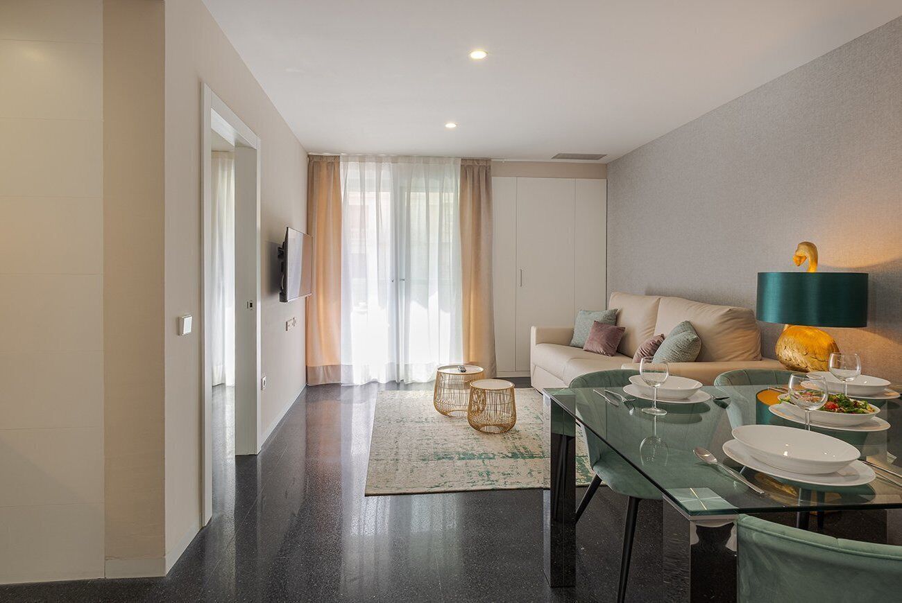 Una sala moderna con una mesa de comedor de vidrio, un sofá y un televisor.