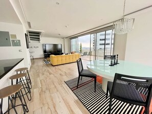 A modern kitchen with a dining area, a yellow sofa, and a large window.