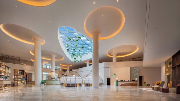 A spacious lobby with a modern design, featuring large circular columns, a central skylight, and a reception area. - Holiday Inn Quzhou by IHG (Quzhou)