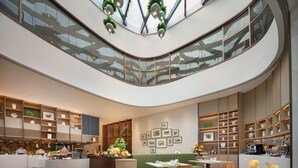 A modern interior with a central seating area, a reception desk, and a variety of framed artworks on the walls. - Holiday Inn Quzhou by IHG (Quzhou)