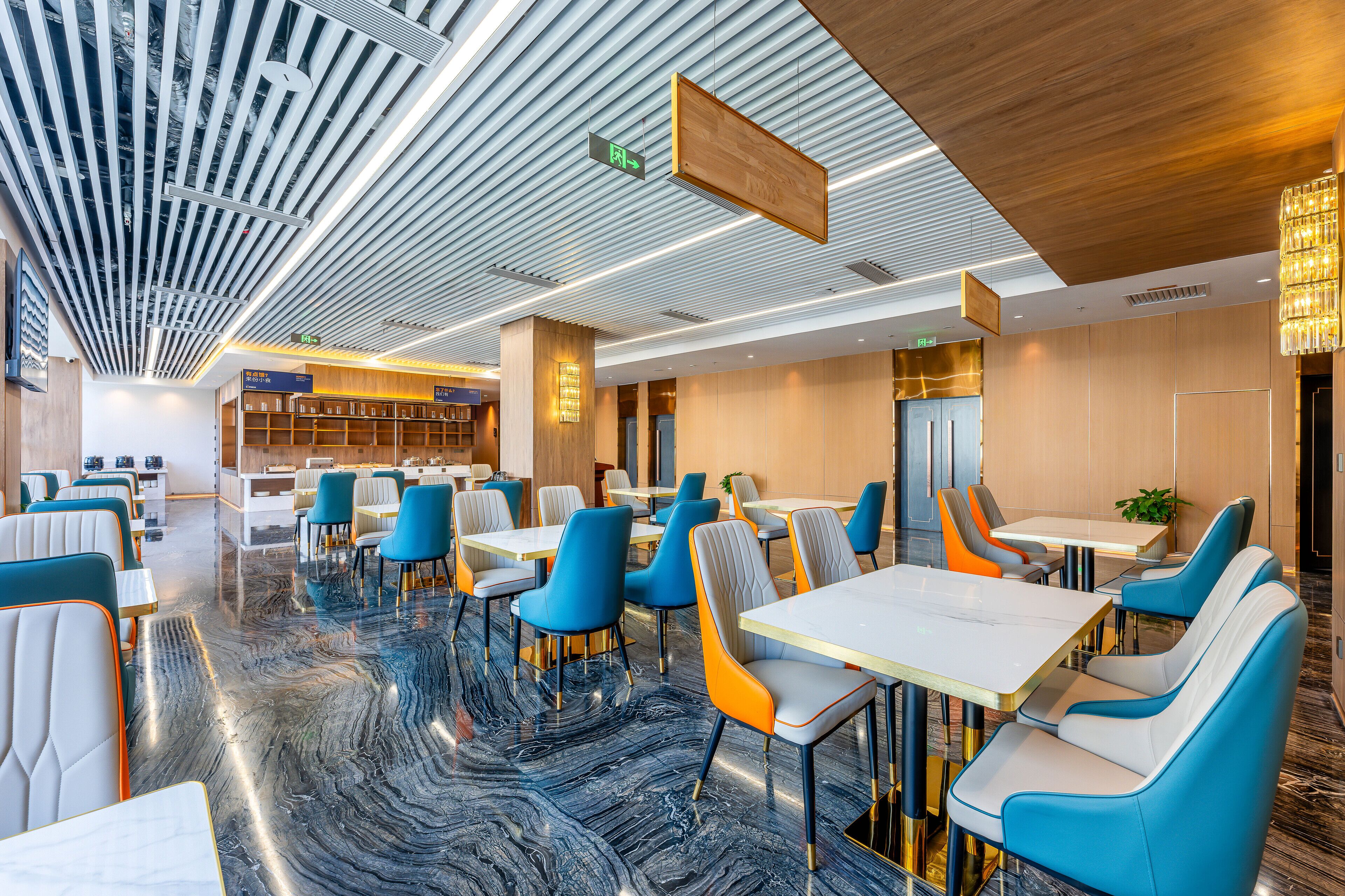 A modern restaurant with marble flooring, blue and orange chairs, and a wooden ceiling.
