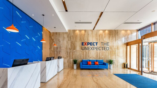 A modern reception area with a marble reception desk, a blue sofa with orange cushions, and a slogan on the wall. - Holiday Inn Express Xi An Guangyuntan by IHG (Xi'an)