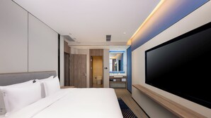 A modern hotel room with a large bed, a flat-screen TV mounted on the wall, a bathroom with a mirror, and a wooden headboard. - Holiday Inn Express Xi An Guangyuntan by IHG (Xi'an)