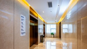 A modern hotel lobby with a directory sign, elevators, and a potted plant. - Holiday Inn Express Xi An Guangyuntan by IHG (Xi'an)