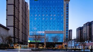 A Holiday Inn Express hotel with a modern glass facade, surrounded by other high-rise buildings. - Holiday Inn Express Xi An Guangyuntan by IHG (Xi'an)