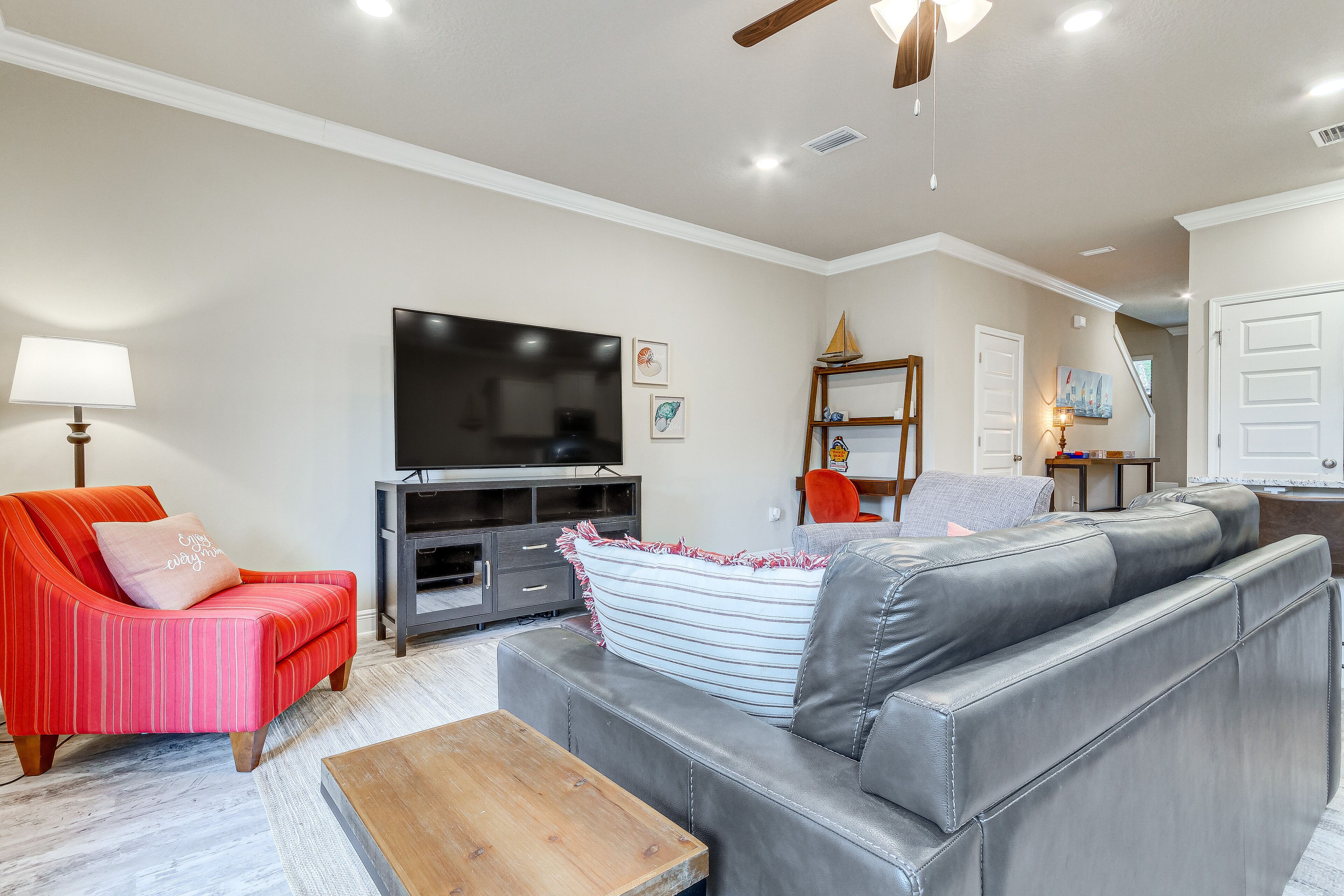 A living room with a grey leather sofa, a red striped armchair, and a wooden coffee table.