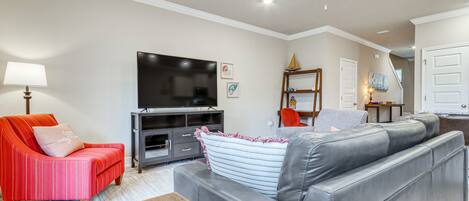A living room with a grey leather sofa, a red striped armchair, and a wooden coffee table.