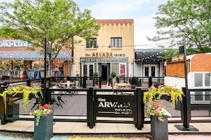 An outdoor seating area with tables and chairs in front of a building with a sign that reads 'the ARVADA tavern.'