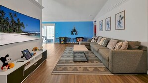 Una sala de estar con un televisor grande, un sofá, una mesa de centro y una pared azul de acento.