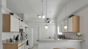 Una cocina moderna con armarios blancos, una isla central y taburetes de madera.