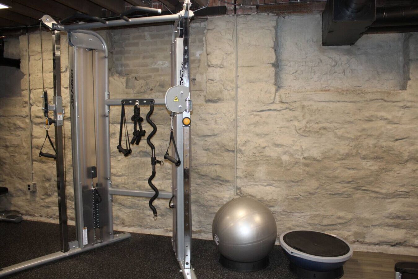 Ein Fitnessraum mit Squat-Rack, Widerstandsbändern, Medizinball und Stehplattform.