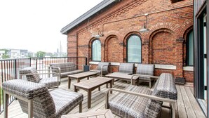 A balcony with wicker furniture and a brick wall. - Stylish Apartment with Urban Charm (Nashville)
