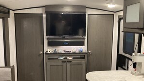 Cocina compacta con una televisión integrada, una pequeña encimera y un armario con un letrero que dice 'BEACH'.