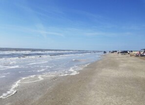 Une plage avec un rivage sablonneux et des vagues de l’océan.