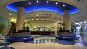 A hotel lobby with a reception desk, two blue seating areas, and potted plants. - 3BD/Daytona - Beach, Pools, Lazy River, Bar, Slides (Daytona Beach)
