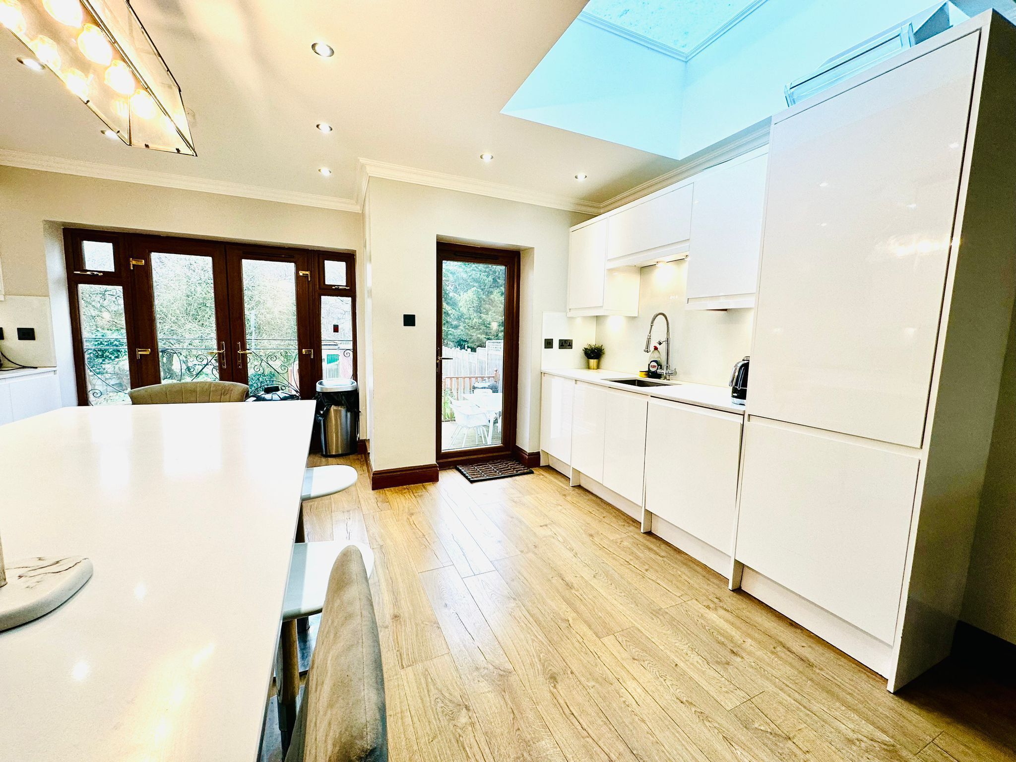 A modern kitchen with white cabinets, a large island, and a skylight.