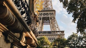 Une vue de rue avec la Tour Eiffel en arrière-plan, un vélo et une moto garés sur le côté.