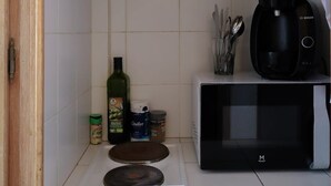 Une cuisine compacte équipée d’un four à micro-ondes, d’une machine à café et d’une petite cuisinière.