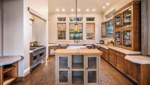 Una cocina amplia con una isla central, muebles de madera y un ventanal con vistas a la vegetación.