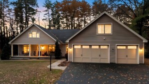A two-story house with a garage, a covered porch, and a driveway. - Luxurious Lake George Getaway (Lake George)
