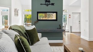 A modern living room with a fireplace, a sofa, and a dining area. - Luxurious Lake George Getaway (Lake George)