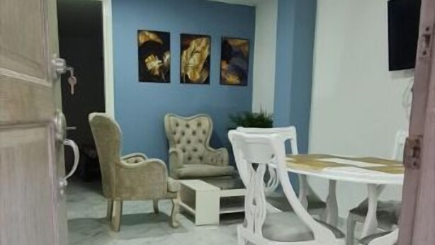 A dining area with a marble floor, a table, and chairs. There are three paintings on the wall. - Apartamento Acogedor en Edificio Privado, el Placer de Sentirse Como en Casa!!! (Barranquilla)