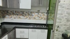 A compact kitchen with grey cabinets, a black countertop, and a tiled backsplash. - Apartamento Acogedor en Edificio Privado, el Placer de Sentirse Como en Casa!!! (Barranquilla)