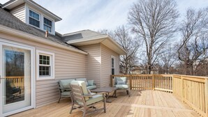 A deck with outdoor furniture, a wooden railing, and a house with large windows and a chimney. - Valhalla View Home-Minutes to Golf Course-Perfect for Golfers, Horses, Trailers (Louisville)
