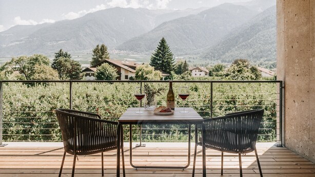 A balcony with a table set for two, overlooking a mountainous landscape. - Traumurlaub: Studio "apfel" auf dem Bio Bauernhof Langstrein (Laces)