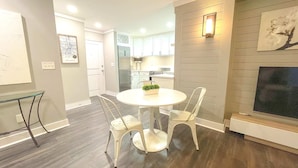 A modern kitchen with white cabinets, a stainless steel refrigerator, and a dining area with a round table and two chairs. - FIFA 2026 Walk to Stadium | 1BR Unit 15L ATL (Atlanta)