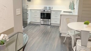A modern kitchen with white cabinets, a stainless steel oven, and a glass dining table. - FIFA 2026 Walk to Stadium | 1BR Unit 15L ATL (Atlanta)