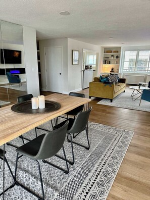 Ett modernt vardagsrum med en matplats, en soffa och en tv som är monterad på väggen.