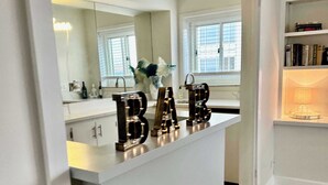 Ein modernes Badezimmer mit Waschtisch, Spiegel und einem Schild mit der Aufschrift 'BAR'.